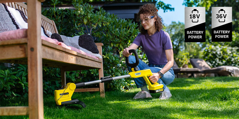 Woman trimming the lawn with battery lawn trimmer