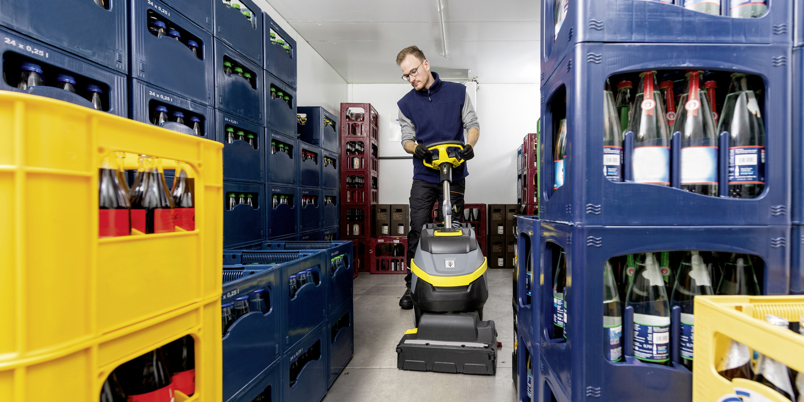 A worker uses floor cleaning equipment inside a cold storage room