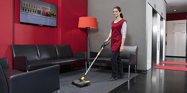 A worker cleans floors in a hotel with a Kärcher compact sweeper