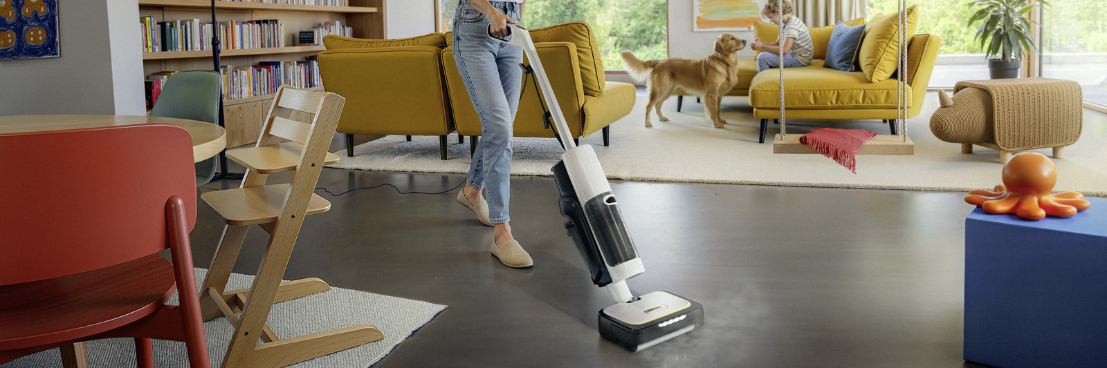 Kärcher Dampfsauger reinigt dunklen Boden im Wohnzimmer mit Hund und gelbem Sofa.