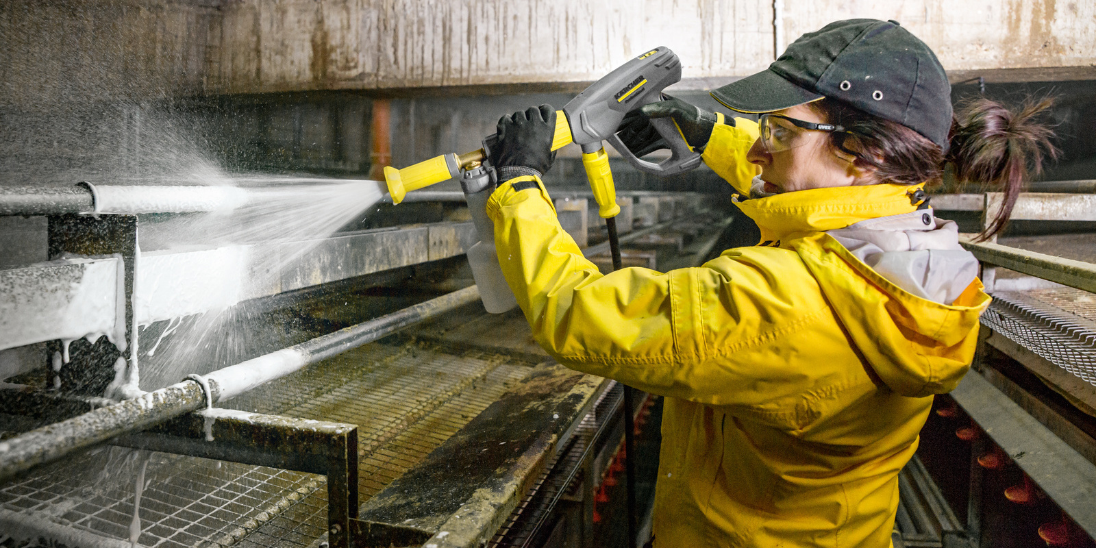 Mulher limpando aviário com água quente e detergente