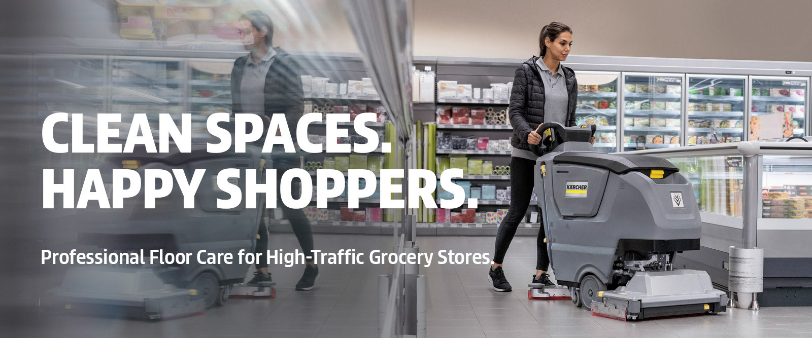 A worker cleans grocery store tiled floors using a walk-behind floor scrubber