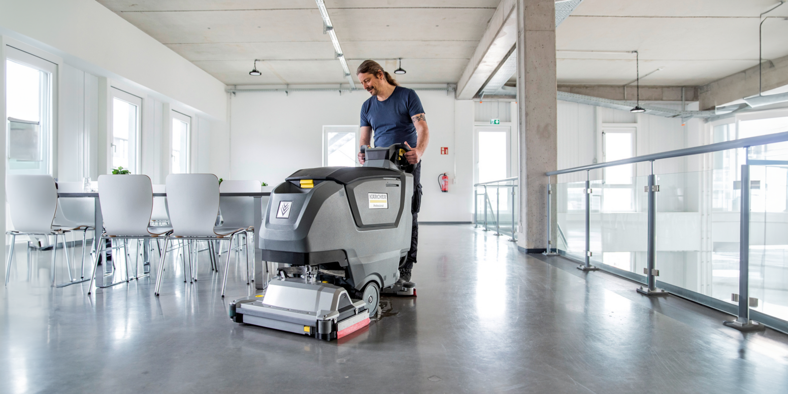Mann sitzt auf Scheuersaugmaschine und poliert Boden.