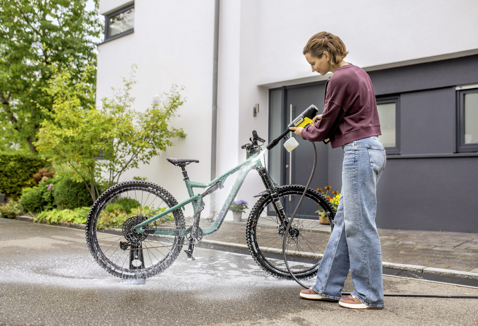 Un homme nettoie son vélo de course avec un pistolet de nettoyage sans fil Kärcher