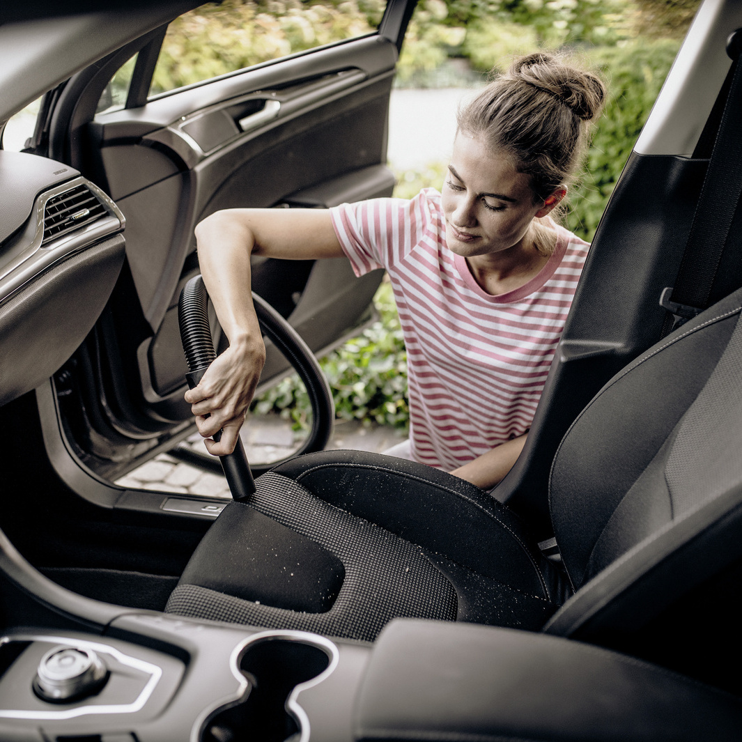 Personne aspirant une voiture avec un aspirateur eau et poussières