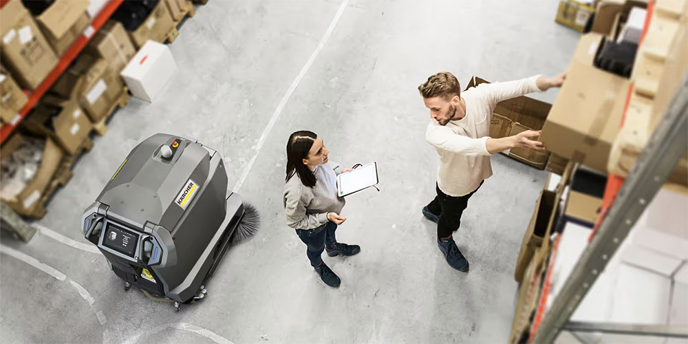 Kärcher KIRA commercial robotic vacuum maneuvering in a warehouse around people