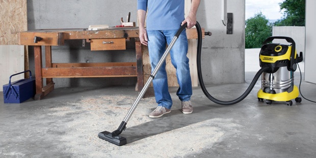 Aspirador multiuso Hombre aspirando serrín del suelo de un taller con un aspirador multiuso