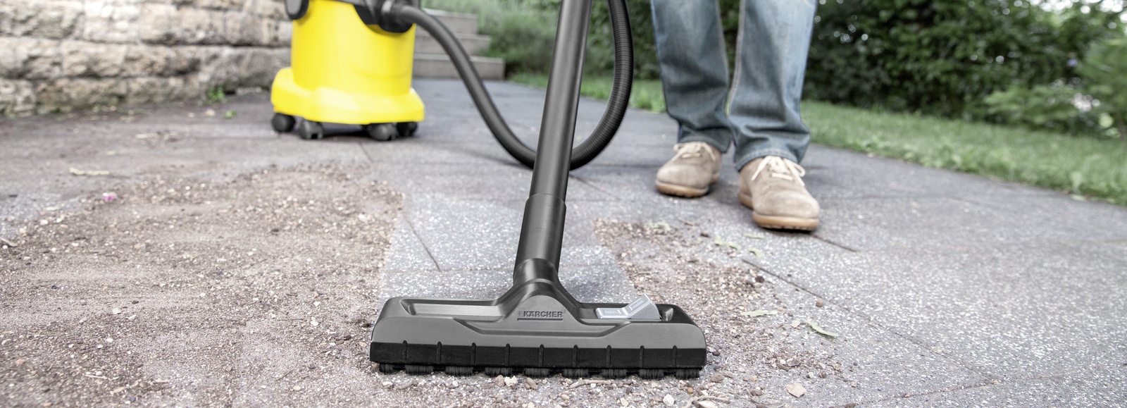 Aspiración suciedad con aspirador multiuso Hombre aspirando suciedad del suelo de un jardín con aspirador multiuso