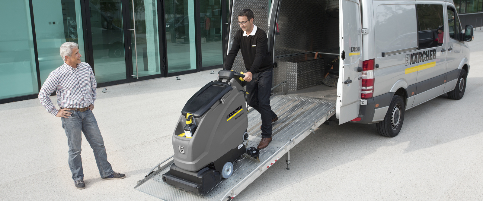 Rental Solutions A man wheels a professional scrubber out of a van for a rental customer.