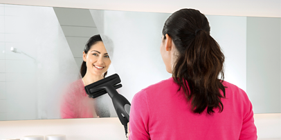 Woman cleaning the mirror using the Kärcher steam vacuum cleaner