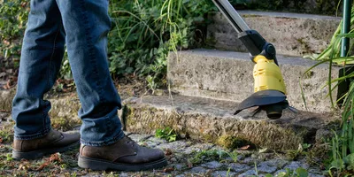 Person removes weeds on a stone staircase with the Kärcher cordless weed remover