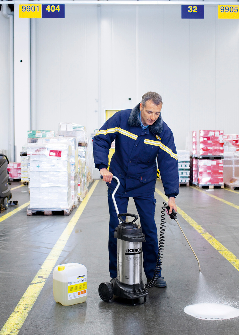 Desinfektion mit Sprühgeräten Mann in Arbeitskleidung desinfiziert den Boden