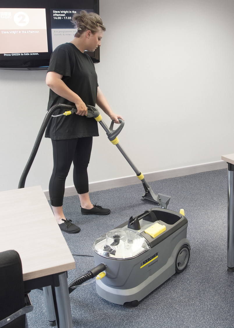 Desinfektion von Textiloberflächen Frau reinigt Teppichboden mit einem Sprühextraktionsgerät