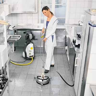 Limpieza a vapor de la cocina con generador de vapor profesional mujer  limpiadora está cocinando al vapor y desinfectando la cocina en la cocina  chica trabajadora del servicio de limpieza doméstica limpia