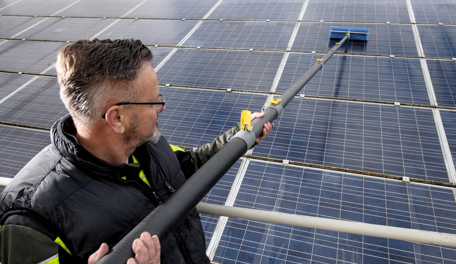 Fassadenreinigung mit der Systemlösung von Kärcher Mann reinigt Solarpanels mit Kärcher Systemlösung für Fassadenreinigung