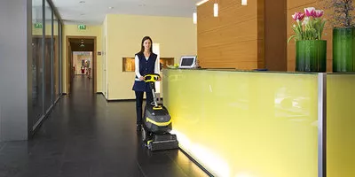 worker cleans hallway with the BR 35/12 walk-behind compact floor scrubber