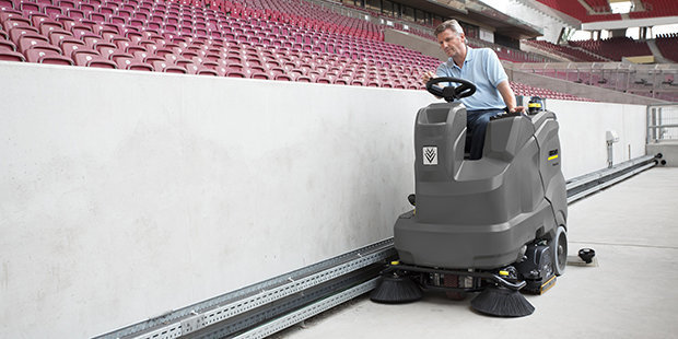 Ride-On Floor Scrubbers worker cleans the lower track of a stadium with the B 150 R Bp ride-on floor scrubber