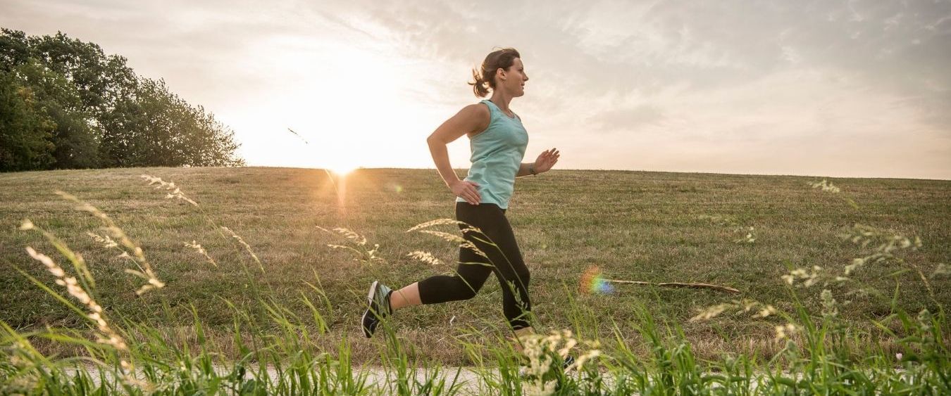 Kärcher Mitarbeiterin Vanessa Helpert joggt bei Sonnenaufgang einen Feldweg entlang. Die Sonne ist gerade am Aufgehen.