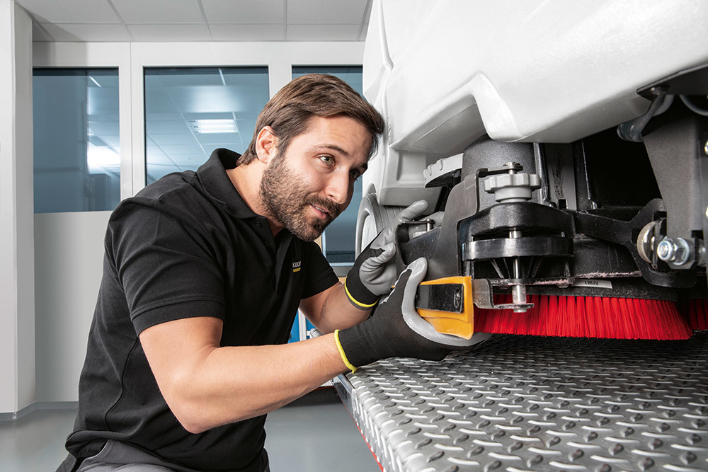 Contact Kärcher for service today! Kärcher service technician repairs a floor scrubber