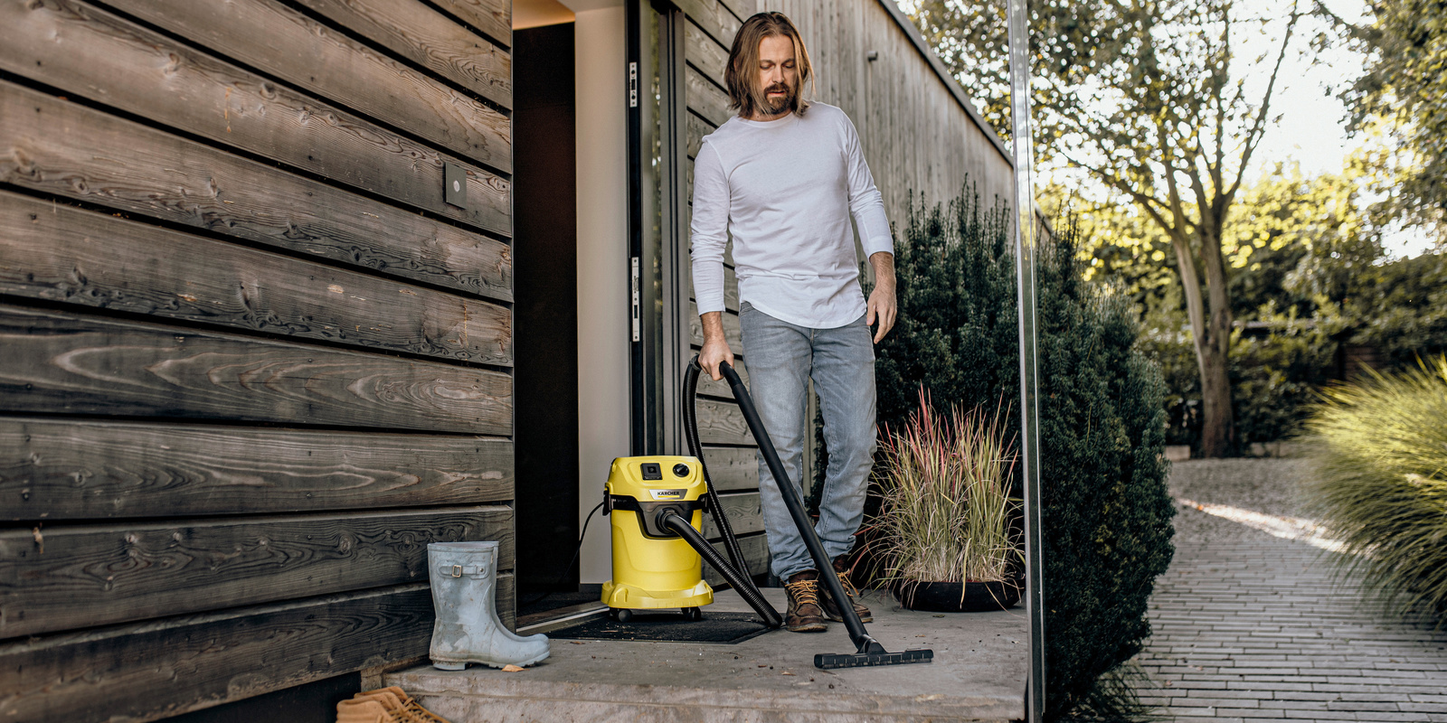 Person vacuums in front of front door Wet and dry vacuum cleaners for outside areas
