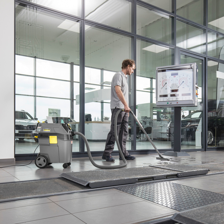Person uses Kärcher wet vacuum cleaner on tiled floor in car dealership Person uses Kärcher wet vacuum cleaner on tiled floor in car dealership