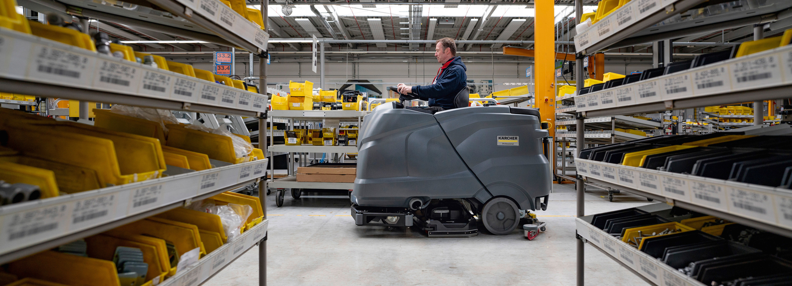 Magazijnvloer wordt schoongemaakt met een Kärcher schrobzuigmachine Man reinigt magazijnvloer met een Kärcher schrobzuigmachine