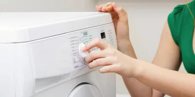 A woman setting the washing machine to the eco programme
