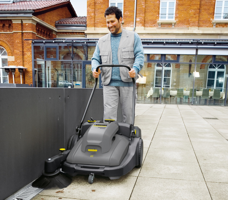 Kärcher floor sweeper in use Man cleans using a Kärcher walk-behind floor sweeper