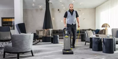 Person cleaning a hotel lobby using a Kärcher Professional vacuum cleaner