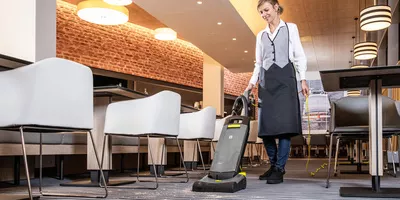 Person cleaning a carpeted floor in a restaurant