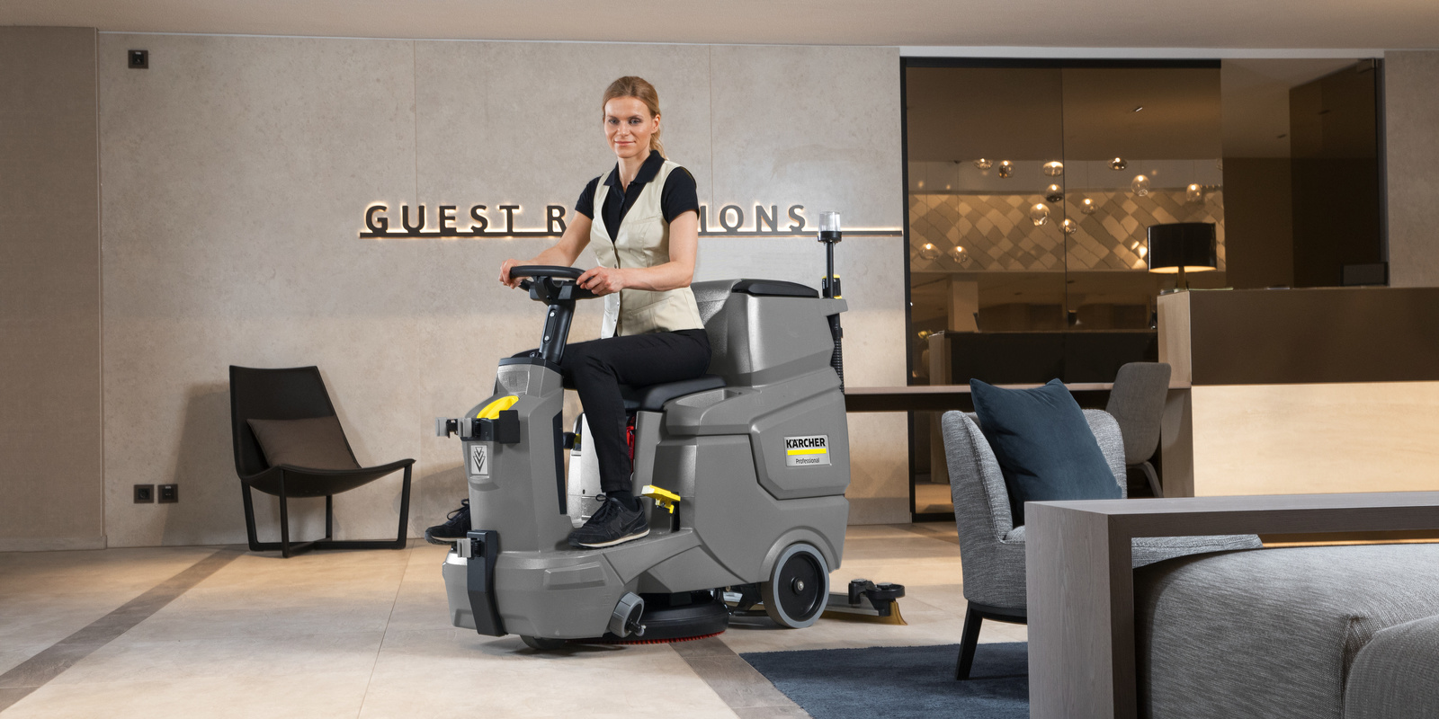 Mujer sobre una fregadora-aspiradora profesional fregando suelo de hotel Mujer sobre una fregadora-aspiradora profesional Kärcher fregando suelo de hotel