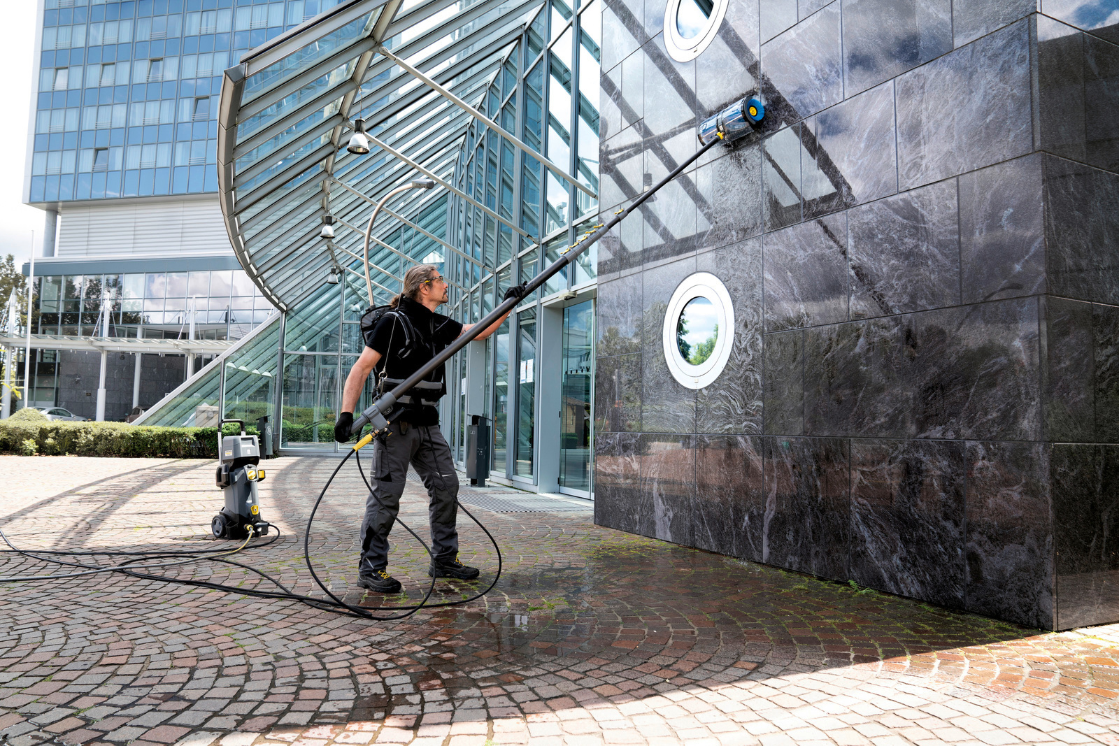 Hombre limpiando una fachada con sistema de limpieza de fachadas de Kärcher 
