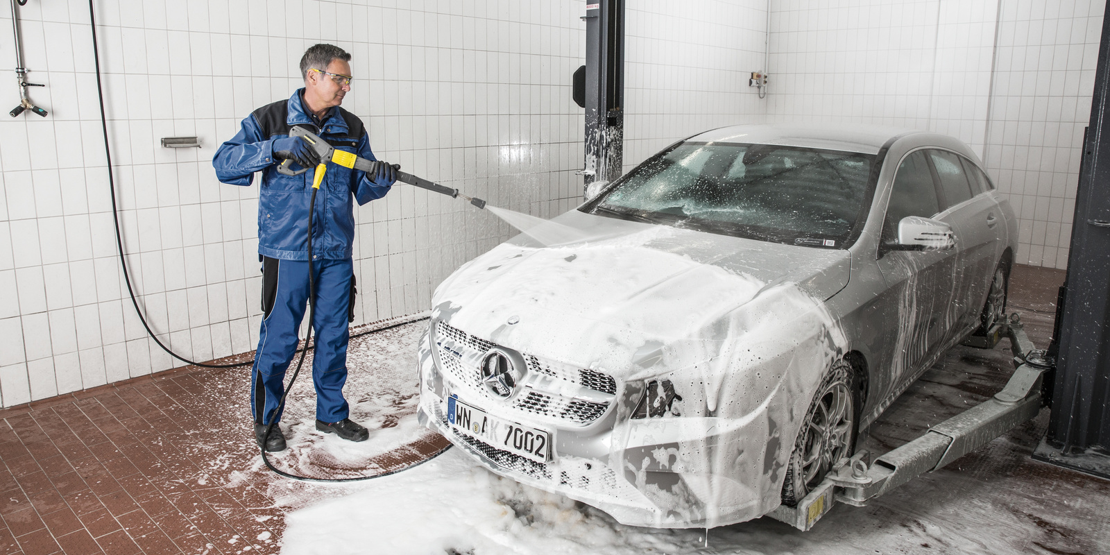Nettoyage d'une voiture avec un nettoyeur haute pression sur une piste de lavage